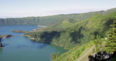 Sete Cidades 'teki bir kraterde güzel bir volkanik göl. Göl, Azores 'in Sao Miguel adasında açık güneşli bir günde ağaçlar ve okyanuslarla çevrilidir. Sol tarafı çevir.