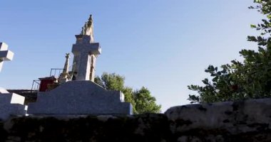 Arka planda uzun bir çan kulesi ve mezarlığı olan bir kilise. Kilise ağaçlarla çevrili ve gökyüzü temiz.