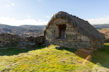 Çimenli bir yamaçta sazdan çatısı olan küçük, yıpranmış bir taş bina var. Bina terk edilmiş gibi görünüyor ve çevre alan büyük oranda boş. Sahne yalnızlık ve sessizliktir.