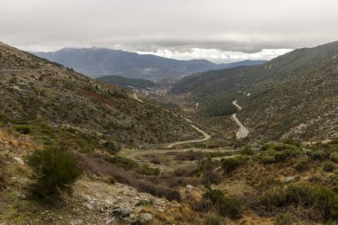 İçinden yol geçen bir dağ sırası. Yol boş ve gökyüzü bulutlu.