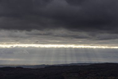 Gökyüzü karanlık ve bulutlu, bulutların arasından bir kaç güneş ışığı görünüyor. Manzara kasvetli ve melankoliktir, bulutlar manzaranın üzerinde belirmeye başlar gibi görünür.