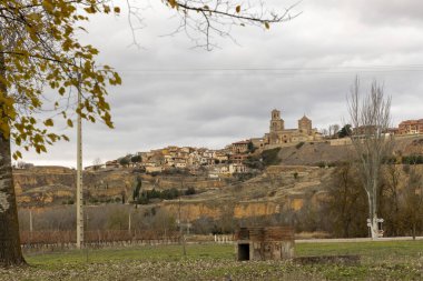 Toro, İspanya, 10 Aralık 2025, kilisesi ve birkaç evi olan küçük bir kasaba. Gökyüzü bulutlu ve yapraklar dökülüyor.