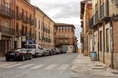 Toro, İspanya, 10 Aralık 2025, üzerinde bir sürü araba olan bir cadde. Arabalar, üzerinde tabela olan bir binanın önüne park edilmiş.
