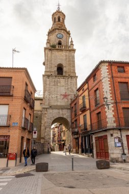 Toro, İspanya, 10 Aralık 2025 'te arka planda saat kulesi olan bir sokak sahnesi. Saat kulesi uzun ve üzerinde bir saat var. Sokakta yürüyen birkaç kişi var..