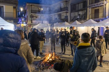 Candeleda, Avila, İspanya, 10 Aralık 2025: Bir grup insan bir avludaki ateşin etrafında toplandı. Atmosfer hareketli ve sosyaldir. İnsanlar orada dikilip birbiriyle konuşur..