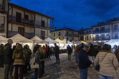 Candeleda, Avila, İspanya, 10 Aralık 2025: Arka planda çadırları olan bir grup insan karanlıkta ayakta duruyor. İnsanlar bir araya toplandıkça sahne hareketli ve sosyal oluyor..