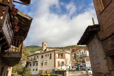 Cuevas del Valle, Avila, İspanya, 10 Aralık 2025: Kilisesi ve saat kulesi olan bir binanın manzarası. Gökyüzü bulutlu ve binalar eski