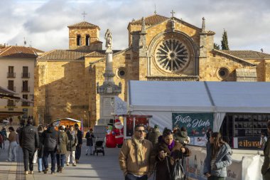Avila, İspanya, 10 Aralık 2025: Önünde büyük bir saatle büyük bir binanın etrafında yürüyen bir grup insan. Bina eski ve uzun bir geçmişi var.