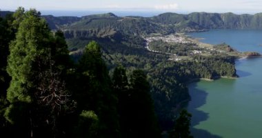 Sete Cidades 'teki bir kraterde güzel bir volkanik göl. Göl, Azores 'in Sao Miguel adasında açık güneşli bir günde ağaçlar ve okyanuslarla çevrilidir. Sağa çevir.