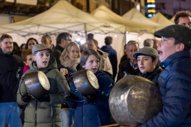 Candeleda, Avila, İspanya, 10 Aralık 2025: Bir grup insan büyük bir tencere tutan bir adamın etrafında toplandı. Çocukların ellerinde daha küçük kaplar var ve hepsi gülümsüyor. Sahne mutlu..