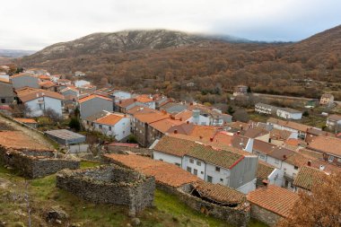 Serranillo, Avila, İspanya, 10 Aralık 2025: Evleri ve arka planda bir dağı olan küçük bir kasaba. Evlerin çoğu beyaz ve kırmızı çatıları var. Kasaba ağaçlarla çevrili ve kırsal bir hissi var.