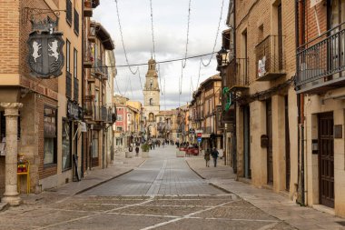 Toro, İspanya, 10 Aralık 2025: Bir sürü insanın dolaştığı ve arka planda yüksek bir binanın bulunduğu bir sokak. Sokak dardır ve bir sürü dükkânı vardır.