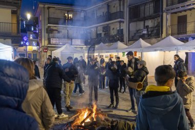 Candeleda, Avila, İspanya, 10 Aralık 2025: Bir grup insan bir avludaki ateşin etrafında toplandı. Atmosfer hareketli ve sosyaldir. İnsanlar etrafta dikilip sıcaklığın tadını çıkarırlar..