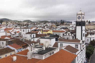 Ponta Delgada, Portekiz, 8 Ekim 2025: Merkezinde saat kulesi olan bir şehir. Binaların çoğu beyaz ve kırmızı. Gökyüzü bulutlu.