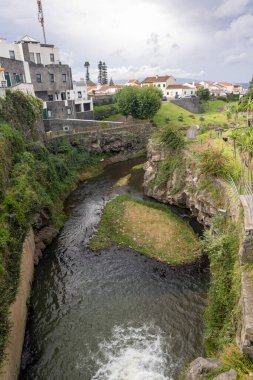 Ribeira Grande, Azores, Portekiz, 8 Ekim 2025: Kayalık bir alandan küçük bir su akıntısı geçer. Su berrak ve sakin, ve çevresi yeşilliklerle dolu..