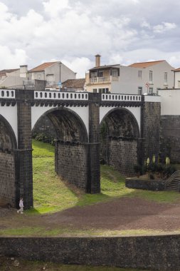 Ribeira Grande, Azores, Portekiz, 8 Ekim 2025: Taş kemerli ve taş duvarlı bir köprü. Köprü, evleri ve kilisesi olan bir kasabada.