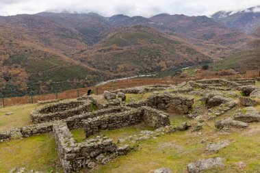 Uzakta bir köyü olan bir dağ sırası. Köy taştan yapılmıştır ve birkaç binası vardır.