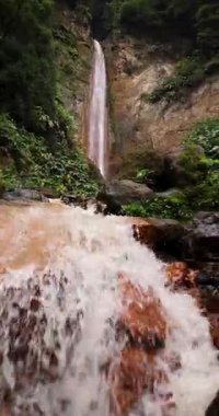 Ribeira Quente yemyeşil bir ormanda büyük bir şelale. Su, Azores Sao Miguel adasındaki bir uçurumdan aşağı akıyor. Sağa kaydırılıyor.