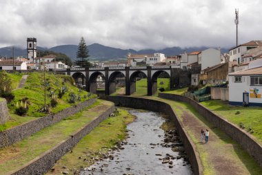 Ribeira Grande, Azores, Portekiz, 8 Ekim 2025: Bir nehir, üzerinde köprü olan bir kasabadan geçer. Köprü eski ve uzun bir geçmişi var. Kasaba dağlarla çevrili..
