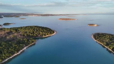 Gün batımında mavi güzel bir denizi olan iki ada arasındaki boğazda uçan drone atışı.