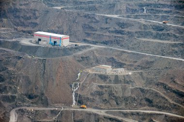 Ağır çöp kamyonları, kazıcılar, kazıcılar ve lokomotifler derin taş ocağında demir cevheri çıkarıyorlar.