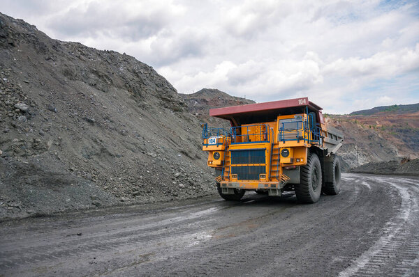 open cast dump truck drives alone industrial area of iron ore quarry