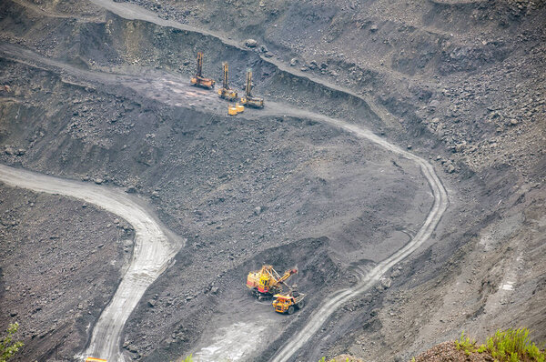 Quarry excavator loading iron ore into the heavy dump truck in iron ore open cast mine