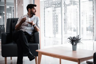 Handsome young bearded businessman with coffee mug