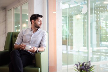 Handsome young bearded businessman with coffee mug