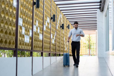 Handsome young bearded businessman with suitcase 
