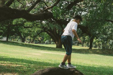 Gözlüklü Asyalı çocuk parkta oynuyor.