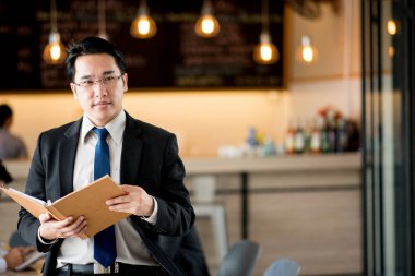 Ofiste kitap okuyan genç bir işadamının portresi.