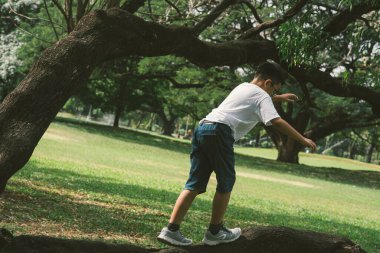 Gözlüklü Asyalı çocuk parkta oynuyor.