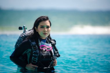 Genç Asyalı kadın dalgıç denizde poz veriyor. 