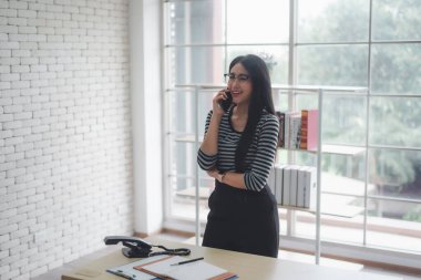 Genç ve güzel bir bayan girişimci cep telefonuyla konuşuyor.