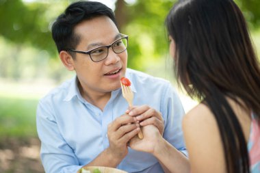 Genç Asyalı çift parkta yemek yiyor.