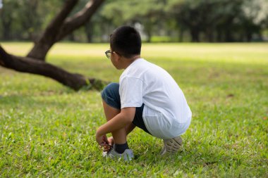 Gözlüklü Asyalı çocuk parkta oynuyor.