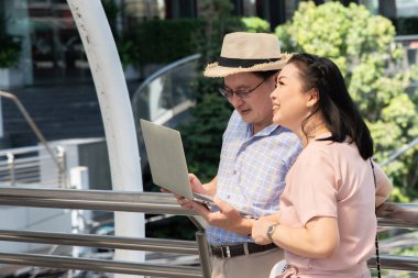 Tren istasyonunda dizüstü bilgisayar kullanan Asyalı çift.