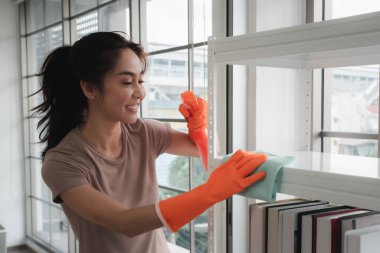 Evde temizlik malzemesi taşıyan genç bir kadın. 