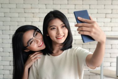 İki Asyalı güzel iş kadını selfie çekiyor.