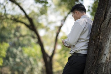 Parkta cep telefonu kullanan genç adam.