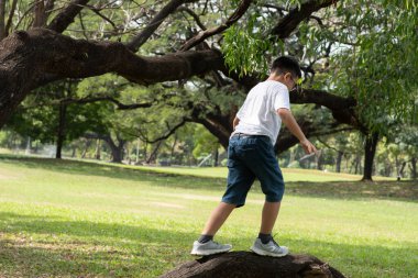 Gözlüklü Asyalı çocuk parkta oynuyor.