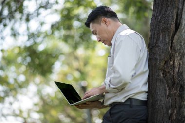 Park yerinde dizüstü bilgisayar kullanan iş adamı