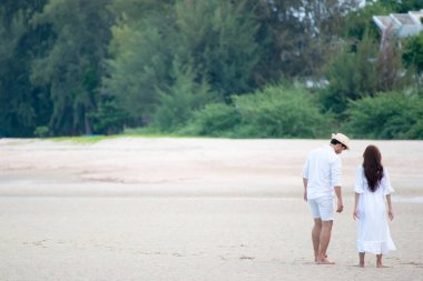 Genç aşık bir çift sahilde yürüyor.