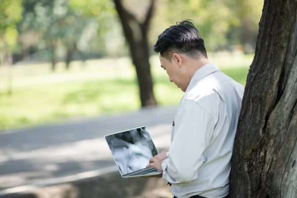 stock image young man using his laptop computer in the park