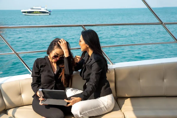 两个亚洲年轻的女商人夏天在游艇上带着数码平板电脑 — 图库照片