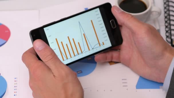 Olhando para diagramas no telefone inteligente — Vídeo de Stock