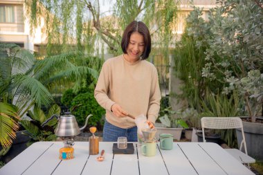 Asyalı bir kadın evinin bahçesinde kahve çekirdeği damlatıyor..