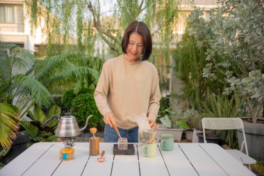 Asyalı bir kadın evinin bahçesinde kahve çekirdeği damlatıyor..