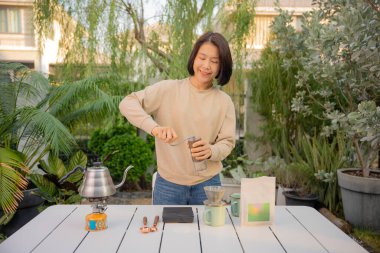 Asyalı bir kadın evinin bahçesinde kahve çekirdeği damlatıyor..